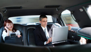 A man sitting in a luxury black while using laptop