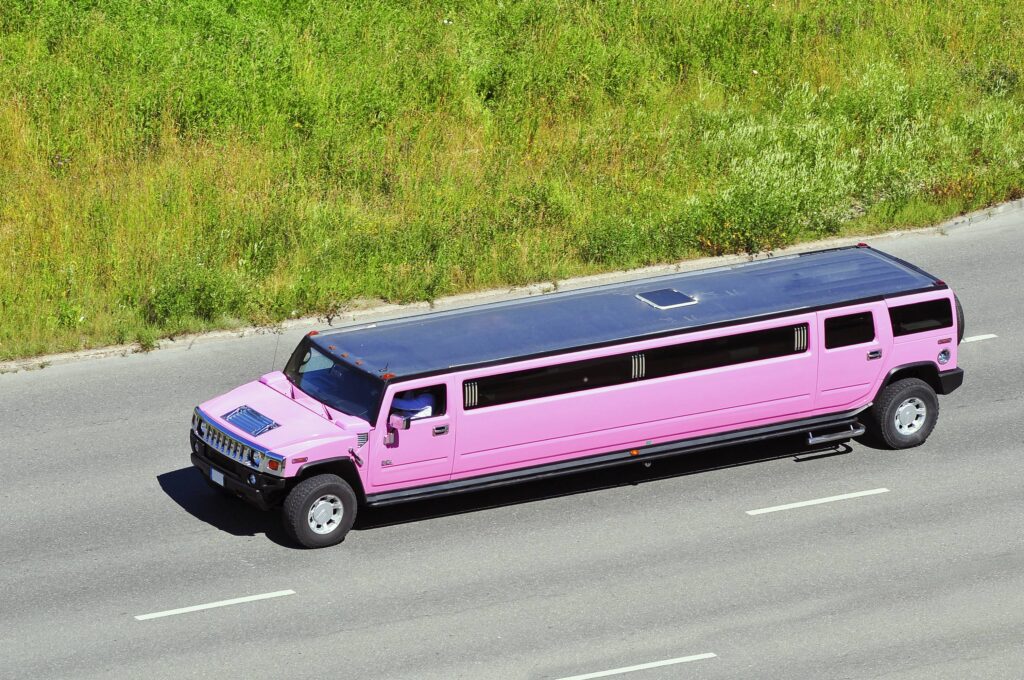 a pink hummer limousine running on an empty road