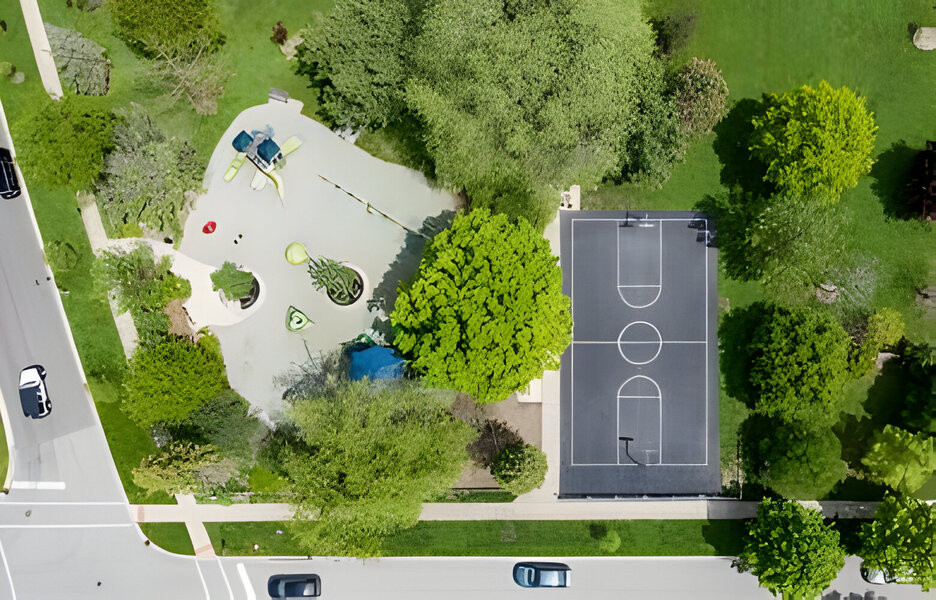 drone view of a local park with playground equipment and a full basketball court in Elmhurst