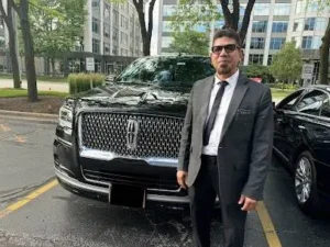 Driver Stands in front of a black Lincoln Navigator