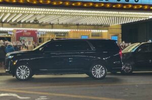 Luxury Black Cars on the Road in front of a lightening building